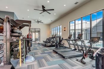 a spacious fitness room with cardio equipment and large windows